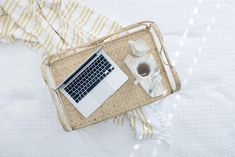 a laptop computer sitting on top of a wooden tray next to a cup of coffee