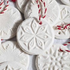 white ornaments with red string on them are sitting on a tablecloth covered in snowflakes