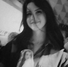 a black and white photo of a woman holding a doll in her hand, with the image of a virgin mary on it's chest