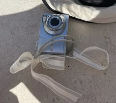 a camera sitting on top of a table next to a white ribbon tied around it