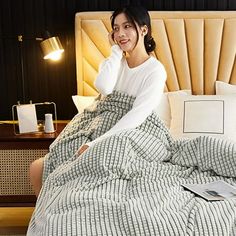 a woman sitting on a bed with a blanket