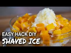 a glass bowl filled with ice cream and mangoes on top of a wooden table