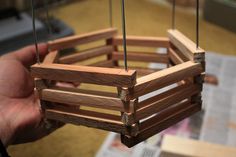 a hand holding a wooden basket with strings