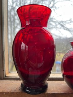 two red vases sitting next to each other on a window sill