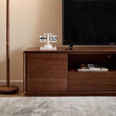 a flat screen tv sitting on top of a wooden entertainment center next to a lamp