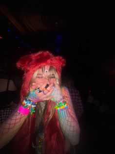 a woman with red hair and colorful makeup covers her face as she poses for the camera