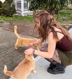 a woman kneeling down petting an orange cat