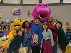 the children are posing for a photo in front of an enormous stuffed animal character with their arms around each other