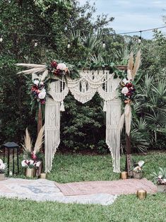 an outdoor wedding ceremony setup with macrame and flowers on the altar, surrounded by greenery