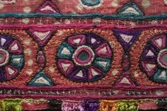 a close up view of an embroidered cloth with different colors and designs on it's edges