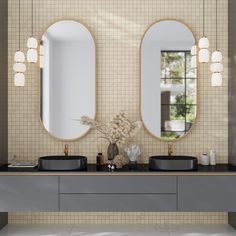 two round mirrors are above black sinks in a bathroom with beige tiled walls and flooring