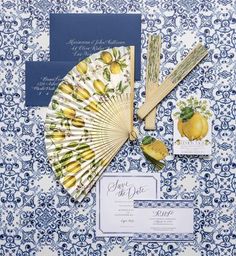 a blue and white wedding suite with yellow flowers, fan, and matching stationery