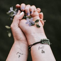 two people holding hands with tattoos on their wrists and flowers in the other hand,