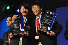 two people standing next to each other holding up their awards for best place in the competition