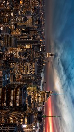 an aerial view of the city lights and skyscrapers at night, with clouds in the sky