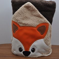 a close up of a stuffed animal hat on a table with a wood surface and wall in the background