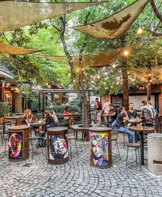 people are sitting at tables in an outdoor cafe