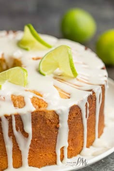 a close up of a cake on a plate with limes around it and white icing