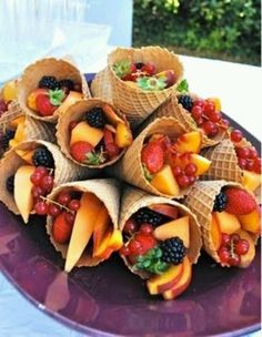 a purple plate topped with cones filled with fruit