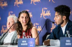 two people sitting at a table with microphones in front of them