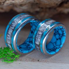 two wedding rings with blue and white marble inlays are sitting next to each other