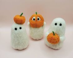 three small white stuffed animals with pumpkins on them