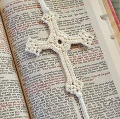 an open book with a crocheted cross on it's cover and the pages are white