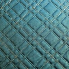 closeup of the stitching on an upholstered blue quilted piece of fabric