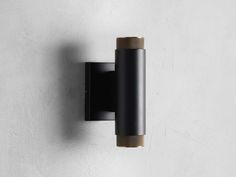 a black wall mounted light on the side of a white wall with a wooden stick sticking out of it