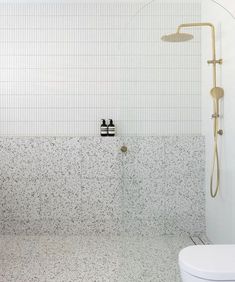 a white tiled bathroom with a shower head and hand held sprayer on the wall