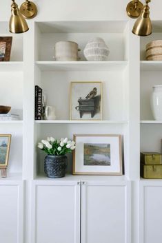 some white shelves with pictures and vases on them