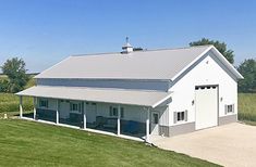 a large white barn sitting on top of a lush green field