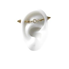 a pair of white ear plugs with gold spikes on each end and an arrow in the middle