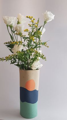 a vase with flowers in it sitting on a table next to a planter filled with greenery