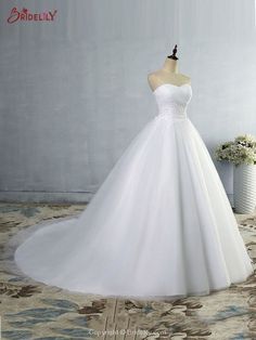 a white wedding dress is displayed on a mannequin in front of a wall