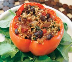 a white plate topped with an orange bell pepper covered in black beans and other toppings