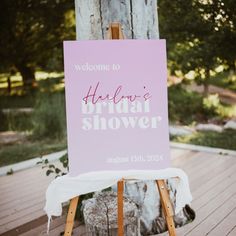 a welcome sign sitting on top of a wooden easel in front of a tree