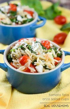 two bowls filled with pasta and vegetables on top of a yellow cloth next to tomatoes