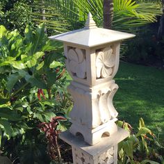 a white bird bath sitting on top of a lush green field next to a palm tree