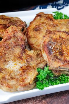 three pieces of meat sitting on top of a white plate covered in green parsley