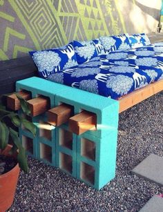 a bench made out of cinder blocks with blue and white fabric on it next to a potted plant