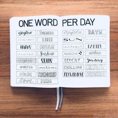 an open notebook with the words one word per day written in black ink on it