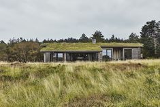 an old building with a green roof in the middle of a grassy field next to trees