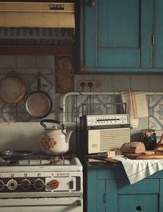 an old fashioned stove top oven sitting in a kitchen next to a teal cabinet