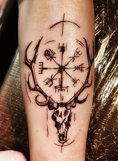 a tattoo on the arm of a person with a deer skull and compass