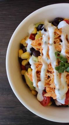 a white bowl filled with taco salad on top of a wooden table