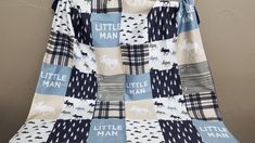 a blue and white quilt hanging on a clothes hanger with the words little man printed on it