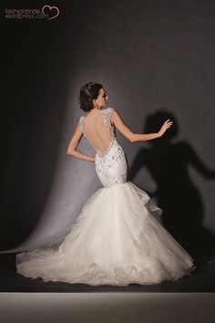 a woman in a white wedding dress is posing with her back turned to the camera