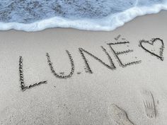 the word june is written in sand at the beach with two hearts drawn on it