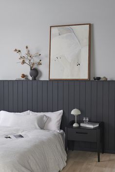 a white bed sitting in a bedroom next to a painting on the side of a wall